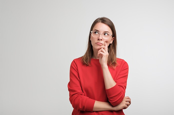Persona con sudadera roja apoyando una mano bajo la barbilla sobre un fondo claro