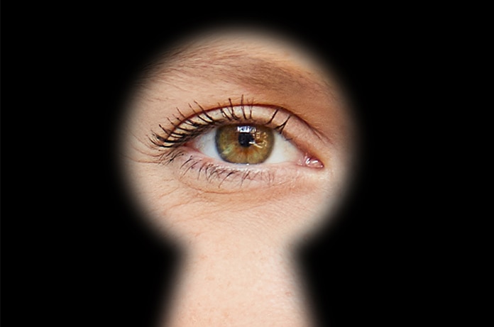 Ojo visto a través de la silueta de una cerradura sobre un fondo completamente oscuro