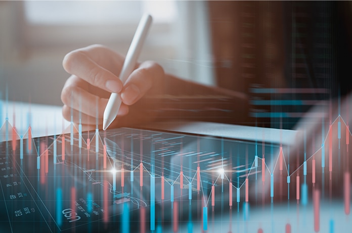 Mano utilizando un lápiz digital sobre una tableta que muestra gráficos superpuestos de líneas y barras en tonos azules y rojos