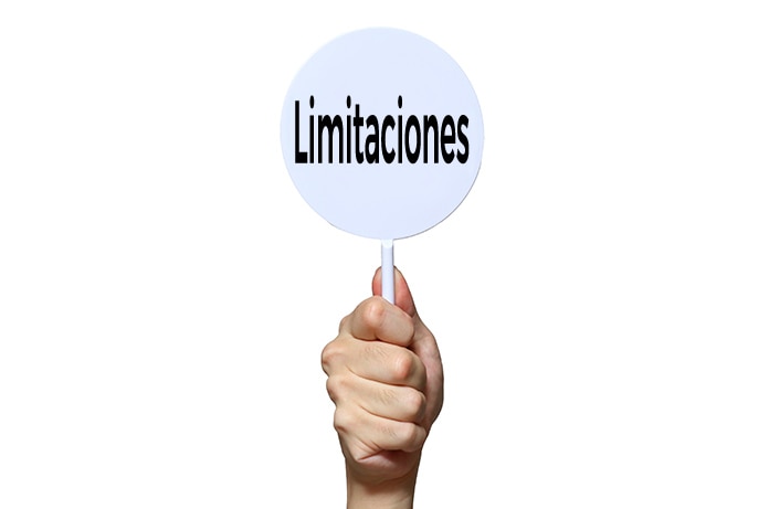 Mano sosteniendo un cartel circular blanco con la palabra “Limitaciones” escrita en negro sobre un fondo completamente blanco