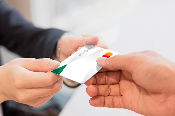 Una persona entrega una tarjeta de El Corte Inglés a otra en un entorno interior iluminado