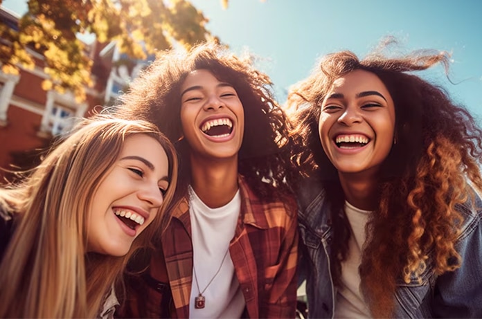 Grupo reunido al aire libre mientras se inclinan hacia la cámara en un entorno urbano con árboles y edificios al fondo